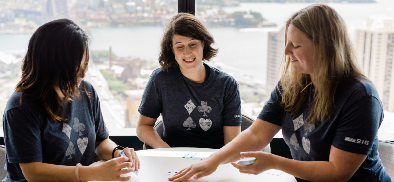 Three women playing cards at a round table