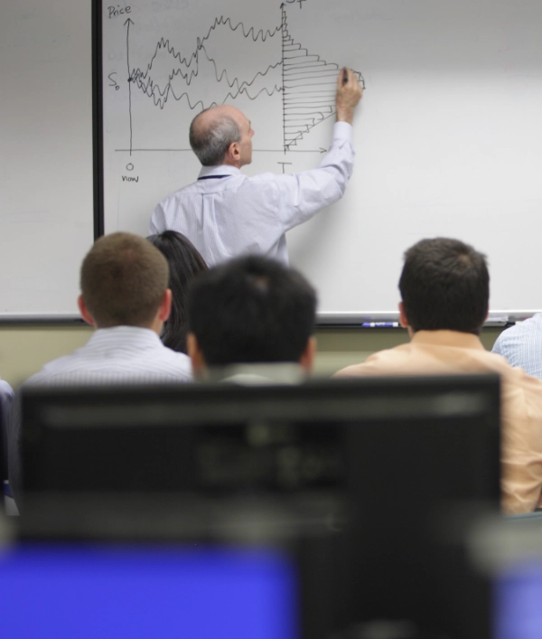 People watching a lecturer draw a graph on a whiteboard