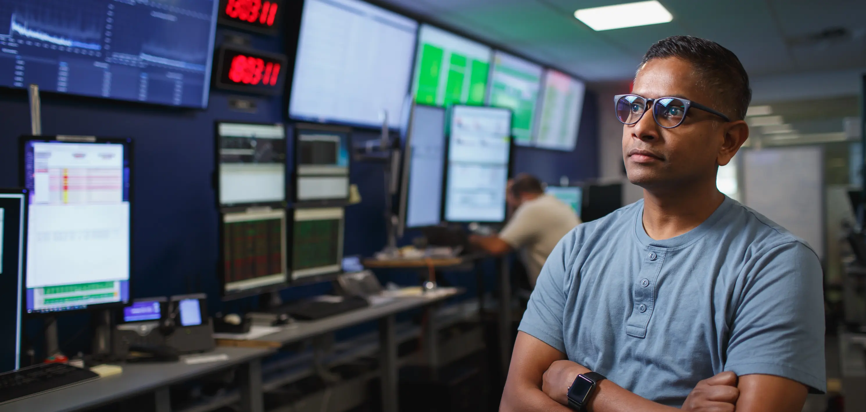 A person in glasses looking off camera into monitors