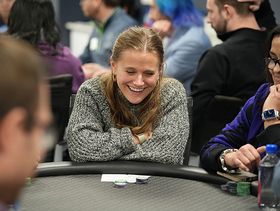 woman in gray sweater laughing playing poker