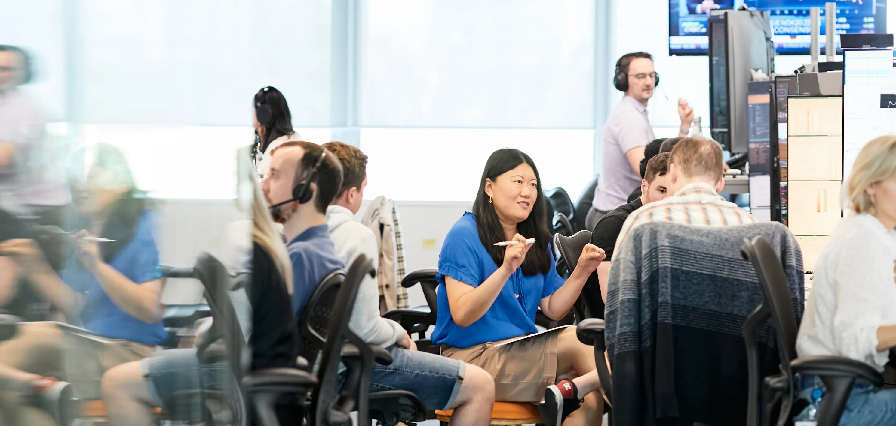 A few people working in the office with one woman talking to coworkers